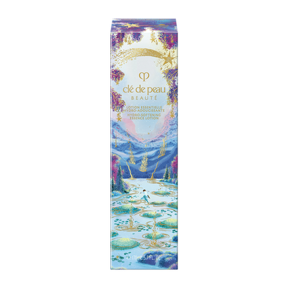 Photo of the 26 AW Holiday Collection limited-edition HYDRO-SOFTENING ESSENCE LOTION outer box. The package shows a person stepping on stones across a blue lake with gold ripples, decorated with a gold shooting star and purple trees at the top.