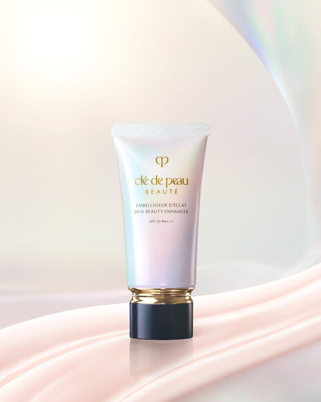 Photo of SKIN BEAUTY ENHANCER in a pearlescent gradient tube with a gold band and black cap, shown with two pale pink product swatches.
Photo of SKIN BEAUTY ENHANCER in a pearlescent gradient tube with a gold band and a blue-black cap.